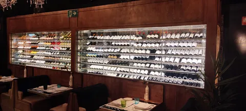 Cava expositora de seis metros integrada en la pared de un restaurante, con botellas iluminadas tras cristal fijo